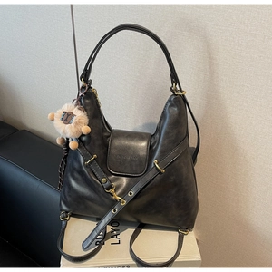 Close-up of black retro tote bag with matte texture, shoulder strap and sheep charm