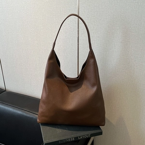 Detail of premium brown pebble grain leather texture on a stylish hobo shoulder bag