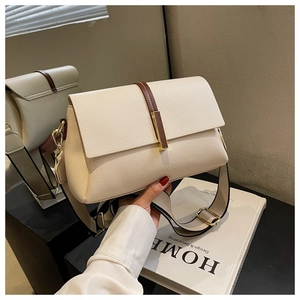 Détail du sac bandoulière en cuir crème avec large sangle et accents métalliques dorés
