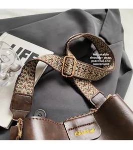 Close-up of adjustable jacquard woven shoulder strap and metal buckle on brown bucket bag