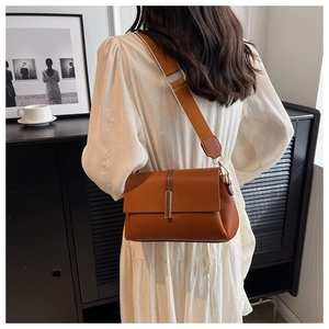 Détail du sac en cuir grainé caramel avec une large bandoulière textile à rayures blanches