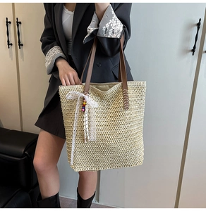 Detail of woven straw tote bag featuring brown leather straps and lace bow with colorful beads