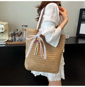 Detail of woven straw tote bag with brown leather strap and decorative lace bow