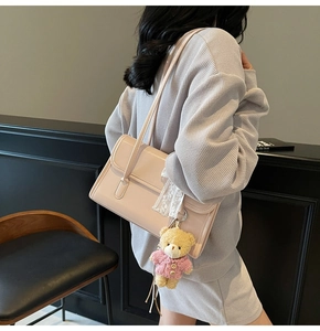 Détail du sac à bandoulière rose en cuir avec dentelle blanche et charm ours mignon