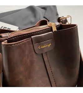 Close-up of vintage brown leather bucket bag showing golden zipper and fine stitching details
