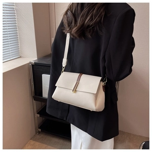 Détail du sac en cuir crème avec bandoulière marron et boucle métallique dorée chic