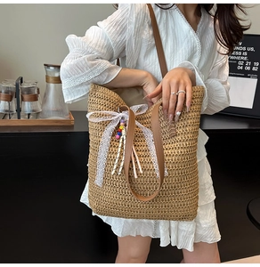 Detail of woven straw tote bag with white lace bow and beaded charms for summer vacation