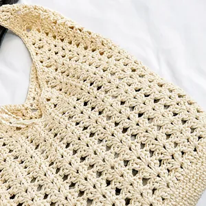 Gros plan détaillé montrant le motif de crochet creux et la texture du sac fourre-tout beige