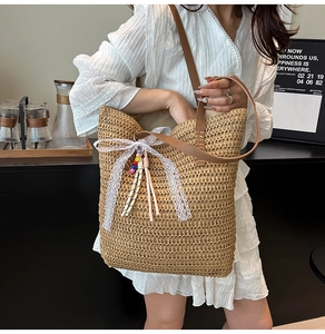 Detail of woven straw tote bag with lace bow, colorful beads and brown leather straps