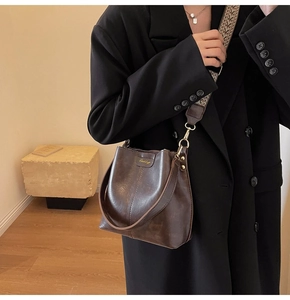 Detail of vintage dark brown bucket bag with bohemian wide strap and leather texture