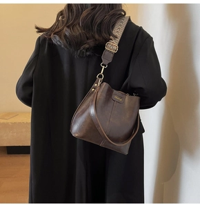 Detail of a dark brown bucket bag featuring an ethnic embroidered wide shoulder strap