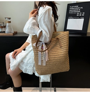 Detail view of woven straw tote bag featuring white lace bow and colorful striped tassels