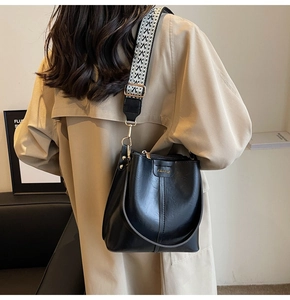 Detail of black leather bucket bag featuring a stylish black and white geometric wide strap