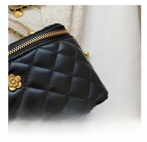 Détail de la texture en cuir noir matelassé et de la chaîne dorée sur ce sac bandoulière