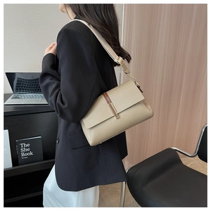 Sac à bandoulière en cuir grainé kaki avec large sangle dans un décor de bureau minimaliste