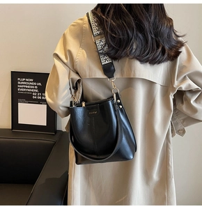 Lifestyle view of black bucket bag with patterned wide strap on female model