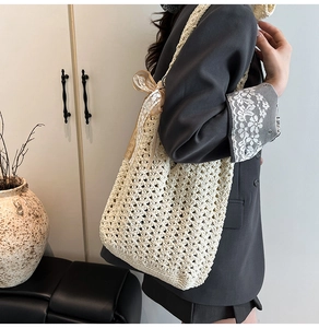 Détail du sac fourre-tout en crochet beige avec un nœud en dentelle sur la bandoulière