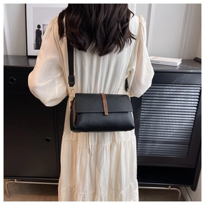 Détail du sac bandoulière en cuir grainé noir avec sangle large et boucle dorée élégante