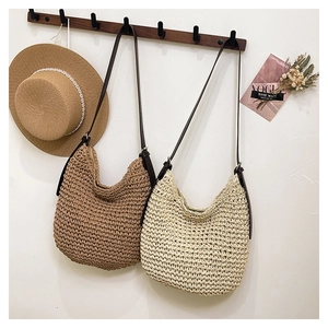 Detail of woven straw bucket bags in khaki and cream with brown leather shoulder straps