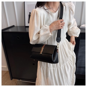 Détail d'un sac bandoulière en cuir grainé noir avec large sangle et boucle dorée