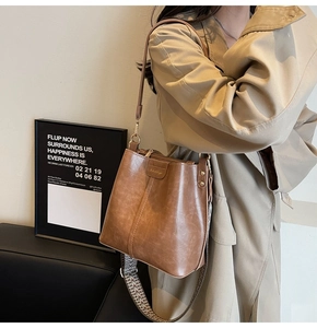 Detail of brown vintage bucket bag featuring stylish wide woven strap and metal hardware