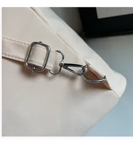 Close-up of silver metal hardware and adjustable canvas straps on a beige backpack