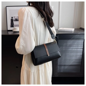 Sac bandoulière noir chic avec large sangle à motifs présenté dans un décor moderne