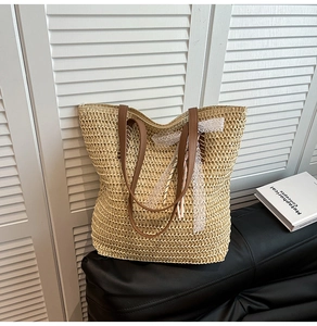 Detail of woven straw tote bag featuring white lace trim and dark brown leather handles