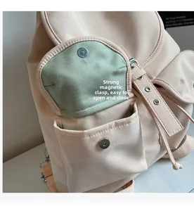 Detail of pink backpack featuring green inner lining and magnetic metal buckle closure
