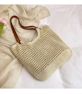 Detail of hand-woven straw tote bag with brown leather straps and mesh texture