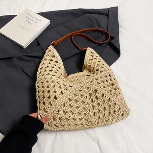 Detail of beige crochet straw tote bag showing large mesh weave and brown leather strap