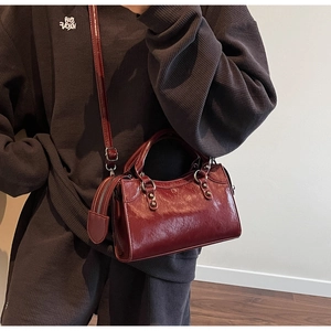 Détail d'un sac en cuir vintage rouge foncé avec clous décoratifs et coutures apparentes