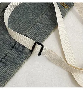 Close-up of adjustable strap buckle on a beige nylon shoulder bag with fabric texture
