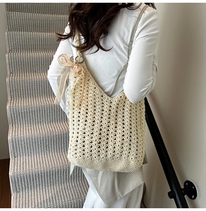 Détail du sac à bandoulière en tricot beige avec nœud en ruban et motifs ajourés