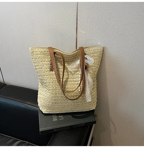 Close-up of beige woven straw tote bag featuring white lace ribbon and colorful bead charms
