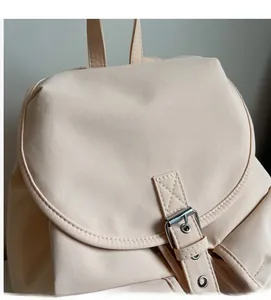Close-up of soft fabric texture and silver buckle closure on a stylish beige backpack