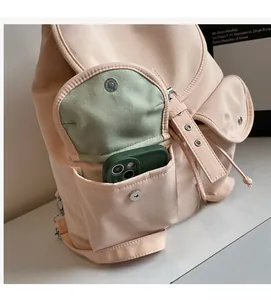 Detail shot of the side pocket of a pink nylon backpack holding a green mobile phone
