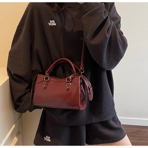 Détail d'un sac en cuir brillant rouge foncé avec rivets argentés et coutures vintage