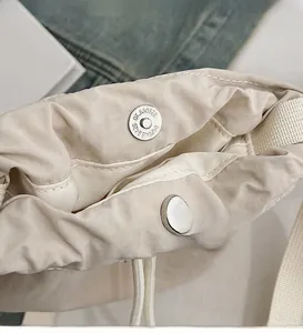 Close-up of high-quality silver magnetic metal buckle closure on beige nylon bucket bag