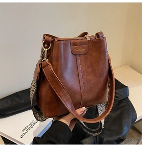 Detail of retro brown bucket bag with wide woven strap and golden zipper hardware