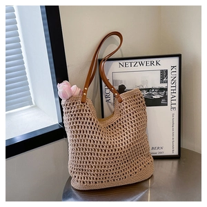 Close-up of the beige straw woven texture and brown PU leather handle with metal rivets