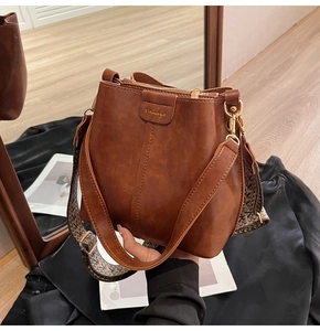 Close-up of brown vintage bucket bag with gold hardware and woven guitar strap