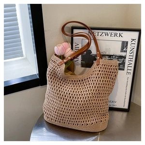 Detailed close-up of beige crochet weave texture and dark brown leather handle on a tote bag