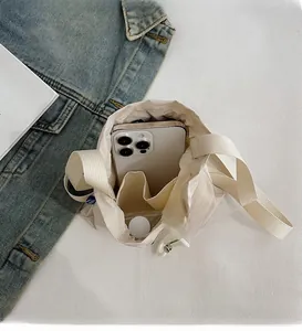 Top view of spacious interior of cream nylon drawstring bucket bag with a smartphone inside