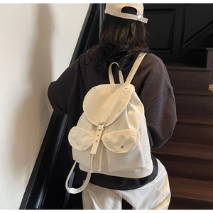 Detail view of off-white canvas backpack with drawstring closure and retro buckle details
