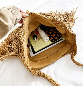 Detail view of large straw tote bag featuring tassel fringe and spacious inner lining