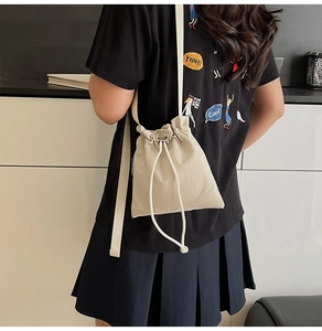 Detail of beige nylon drawstring bucket bag with metal eyelets and textured fabric pleats