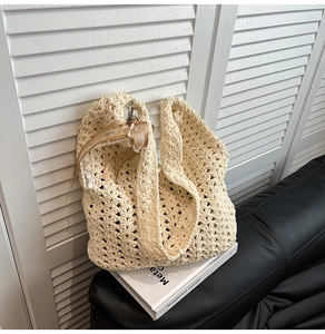 Détail du sac hobo en crochet beige ajouré avec ruban de dentelle décoratif sur livre