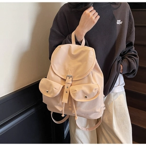 Close-up of a stylish beige drawstring backpack with flap and metal buckle details
