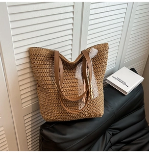 Detail of woven straw tote bag with brown leather handles and decorative white lace ribbon